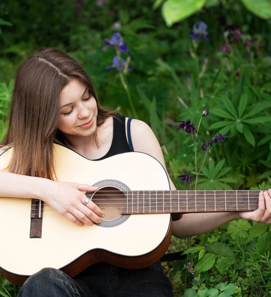 Donate to Spoke 18; young woman playing guitar